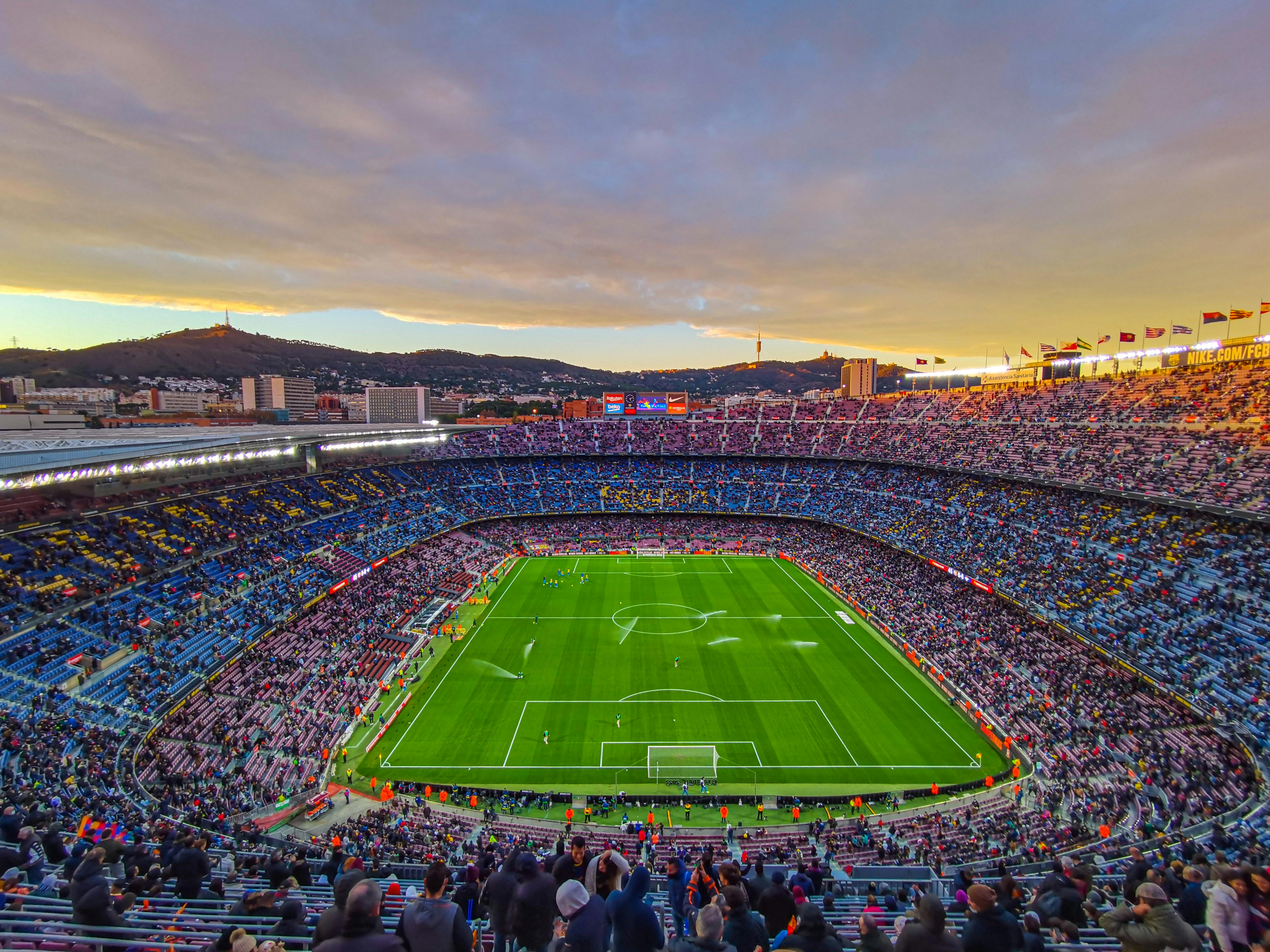Spectacular packed soccer stadium at golden hour with thousands of fans